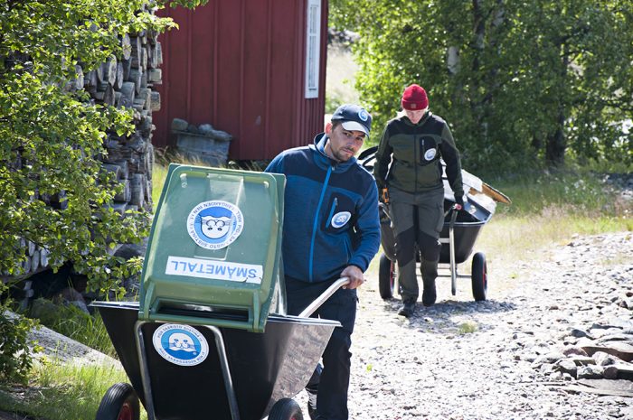 Vapaaehtoiset kuljettavat roskia kottikärryissä.